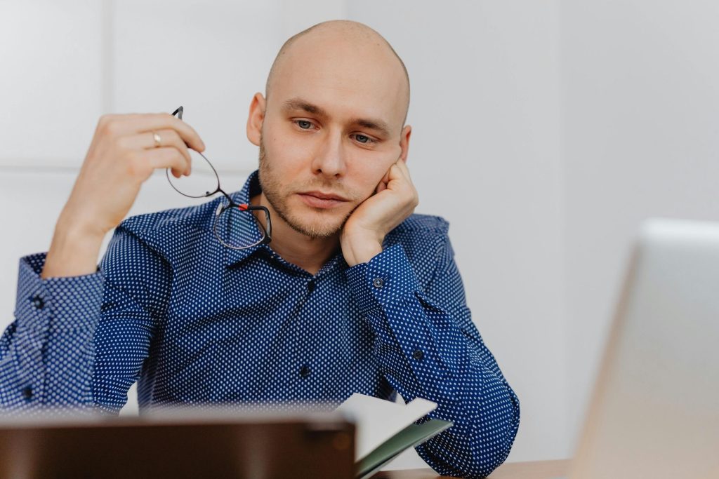 Man in a library examines his eyeglasses