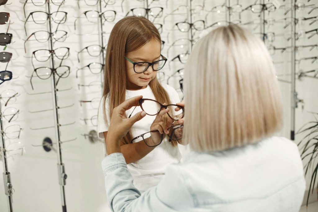 An older woman helps a girl choose eyeglasses