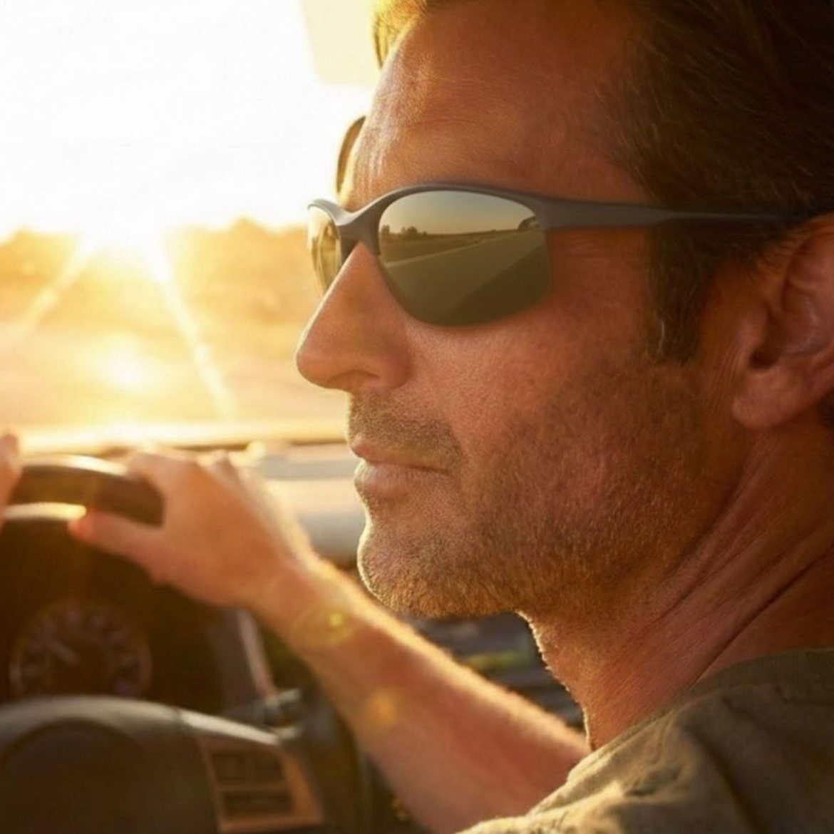 Man wearing sunglasses as he drives into the sun