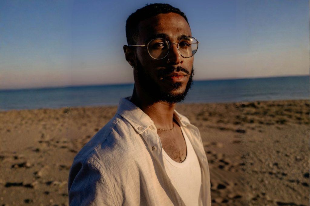 Man on the beach wearing round glasses