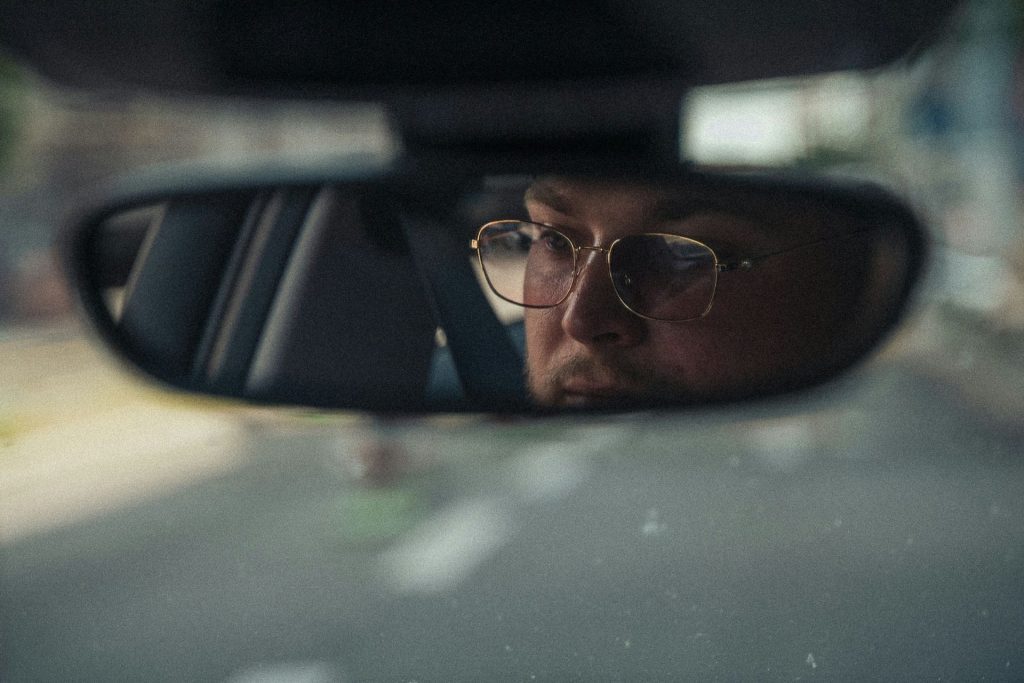 Man driving wearing gold-framed glasses