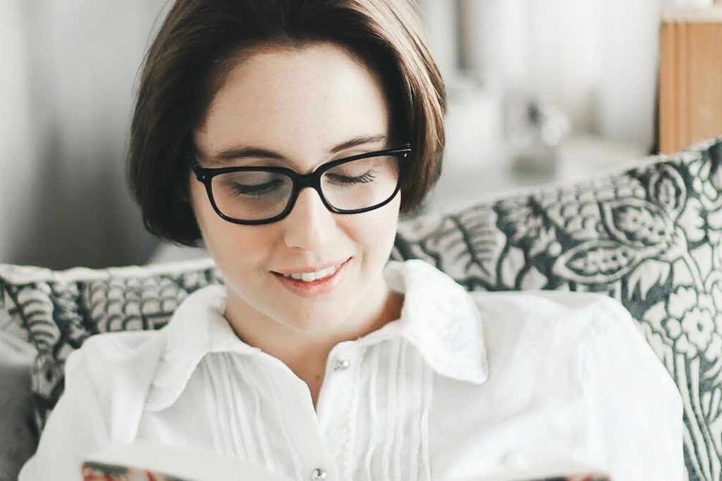 Woman reading a book while wearing glasses