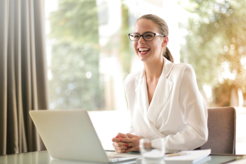 Woman on a laptop wearing glasses and smiling