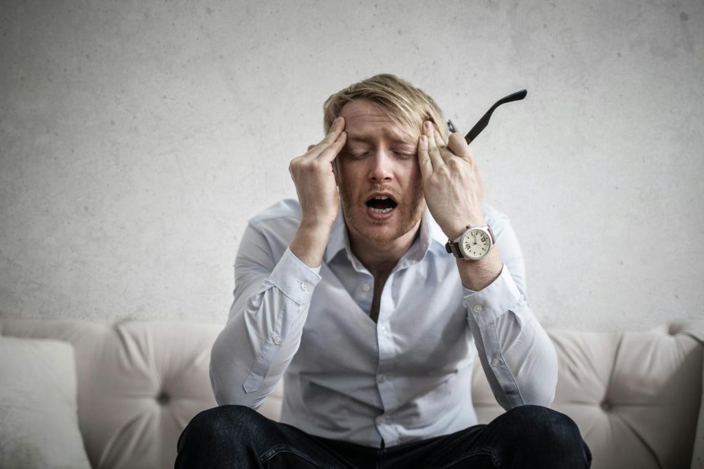 Man holds glasses and head