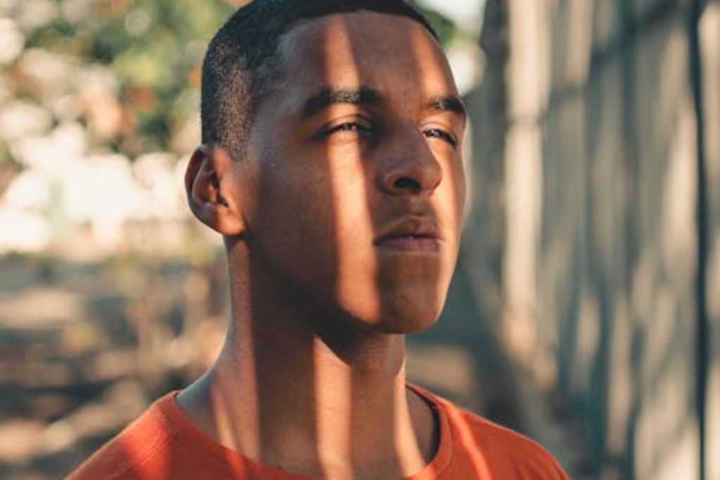 Man with oval face stands in sunlight