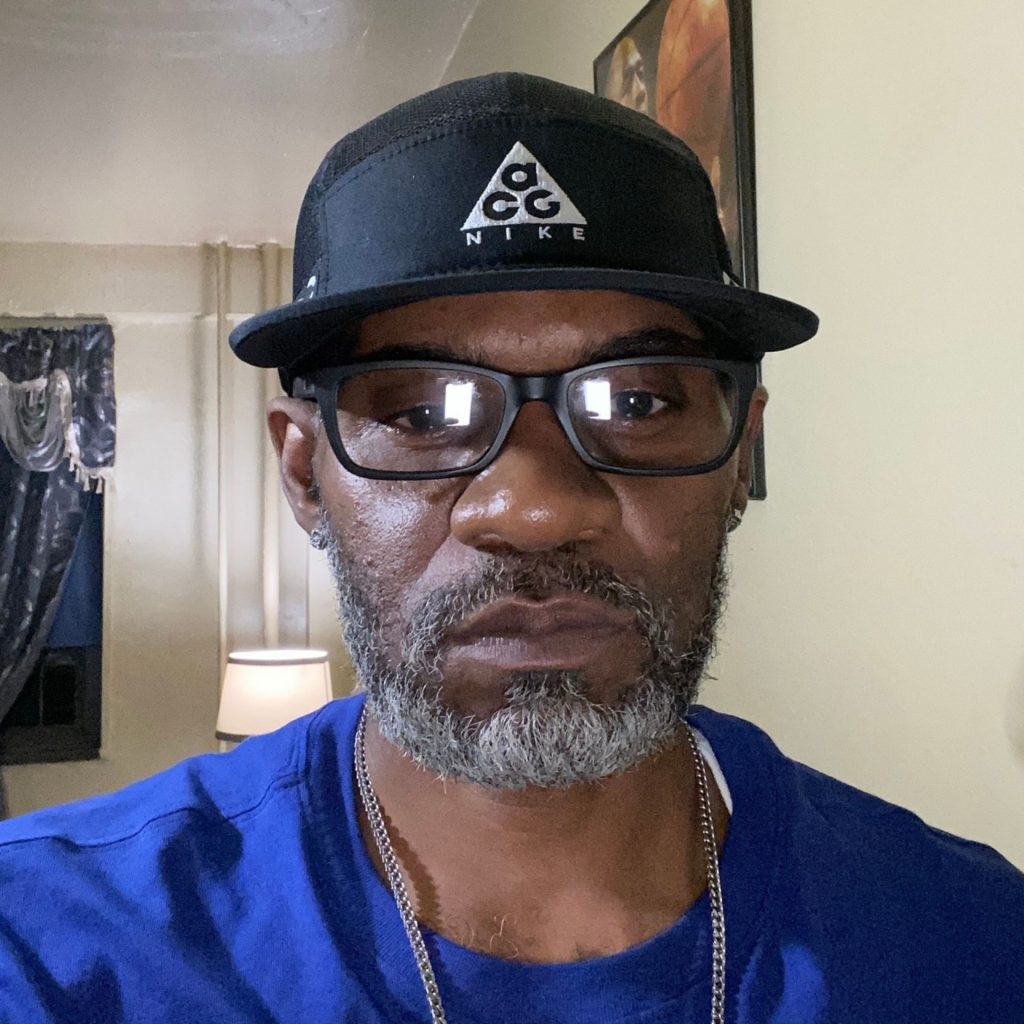 Man wearing a baseball hat and black Armani Exchange AX3007 rectangular glasses