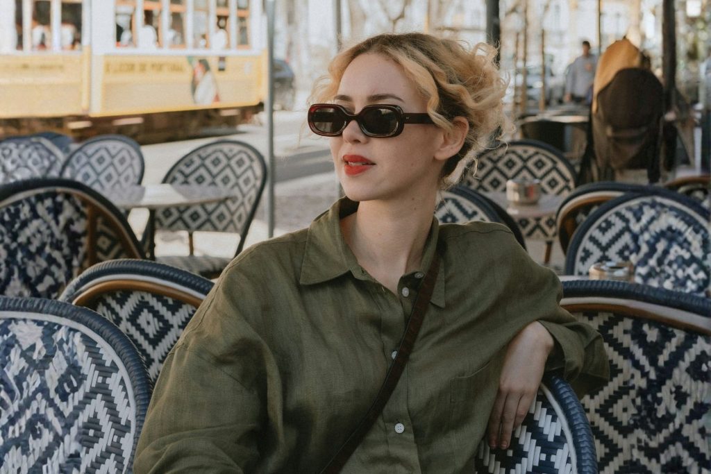Woman wearing oval sunglasses sitting at table at restaurant