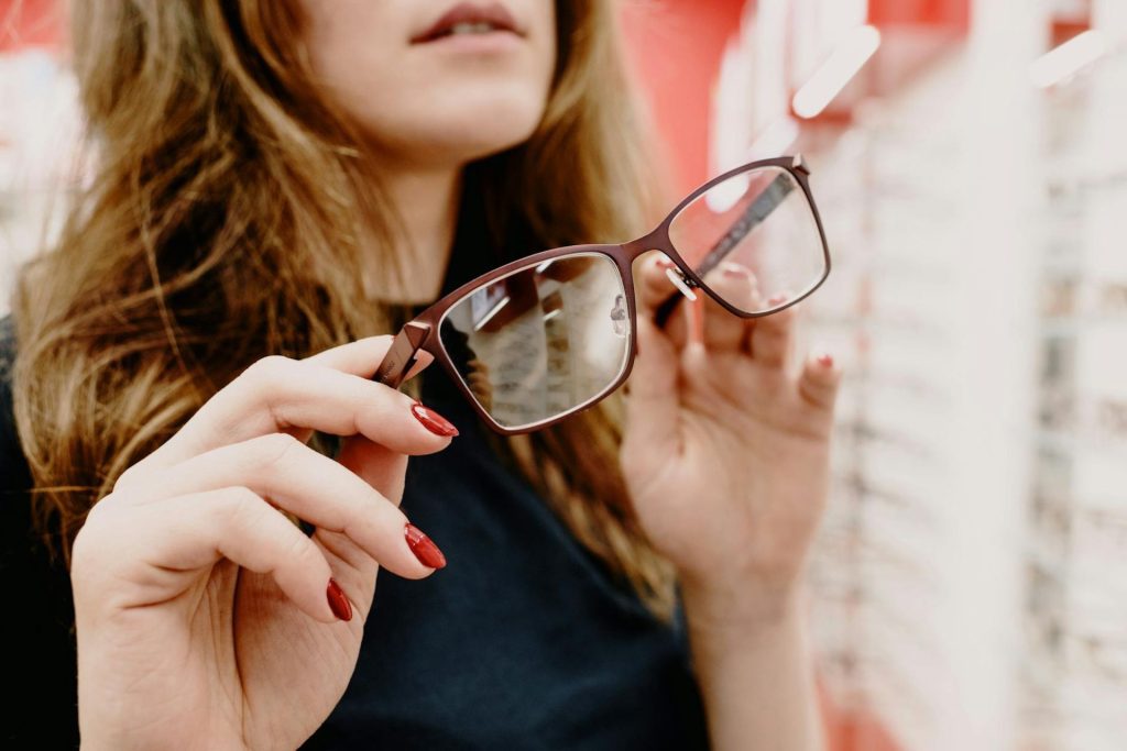 Woman in a black shirt holds a pair of glasses with brown frames