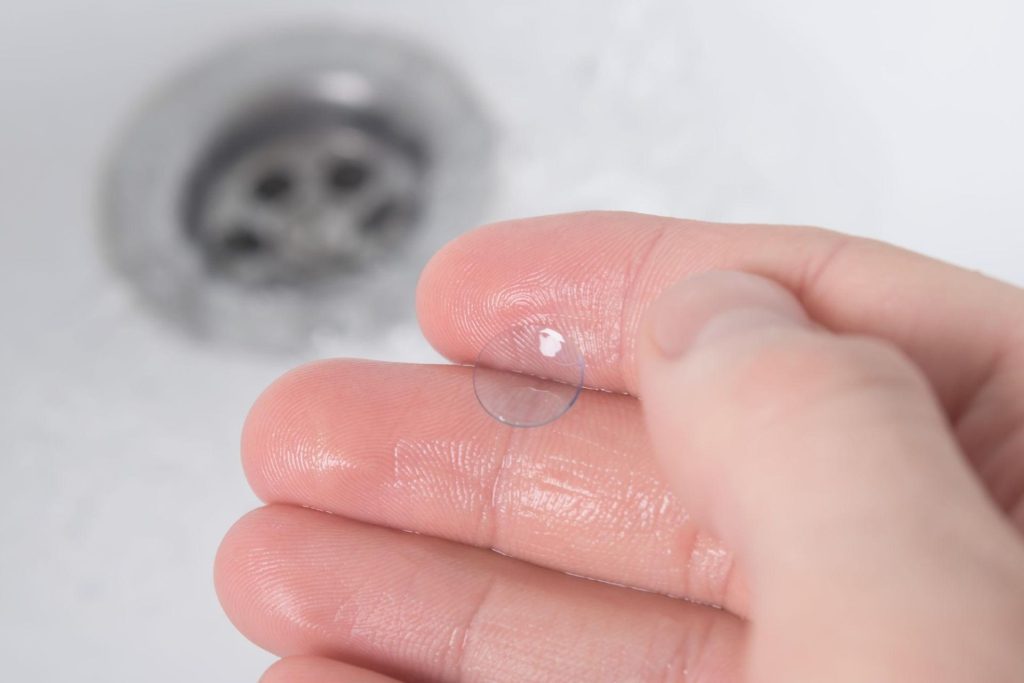 A wet hand holding a contact lens