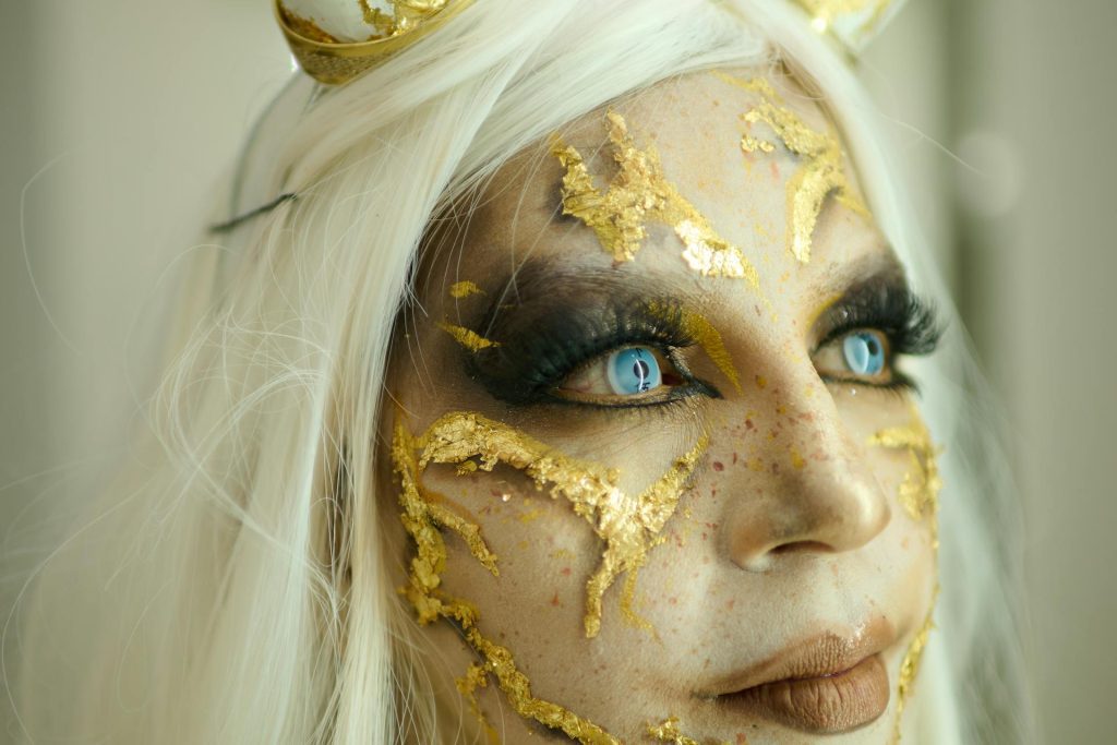 Woman wearing gold makeup and blue contacts